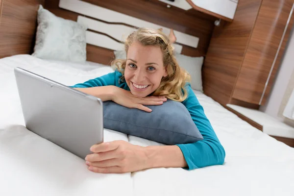 ベッドの上のタブレットで幸せな若い美しい女性 — ストック写真