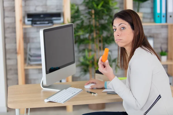 Όμορφη Νεαρή Γυναίκα Τρώει Καρότο Στο Γραφείο — Φωτογραφία Αρχείου