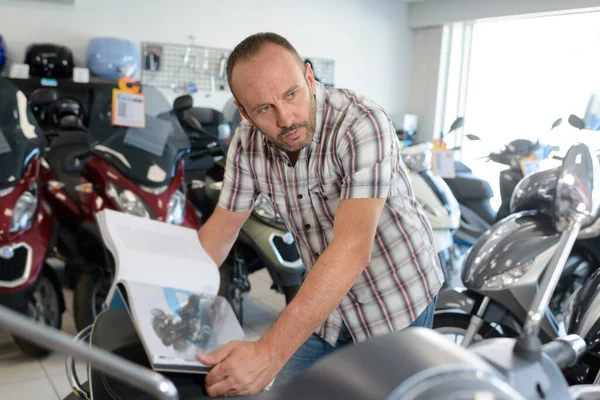 Человек Салоне Мотоцикла Сравнивает Велосипед Изображением Книге — стоковое фото