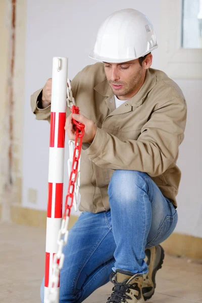 一个男建筑工人正在安装一些铁链 — 图库照片