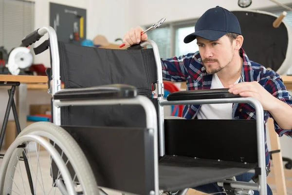 Ανάπηρος Επισκευάζοντας Αναπηρική Καρέκλα Στο Εργαστήριο — Φωτογραφία Αρχείου