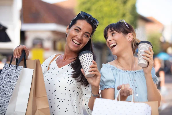 两位女士提着包和咖啡享受一些零售疗法 — 图库照片
