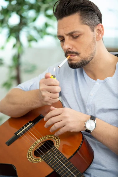 Schöner Mann Raucht Zigarette Während Eine Akustikgitarre Der Hand Hält — Stockfoto