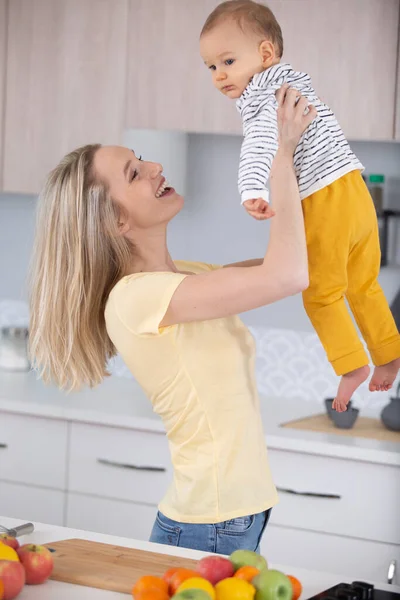 Γυναίκα Στην Κουζίνα Σηκώνει Παιδί Της Στον Αέρα — Φωτογραφία Αρχείου