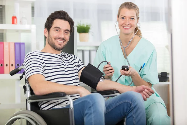 Junge Attraktive Krankenschwester Überprüft Den Blutdruck Von Behinderten — Stockfoto