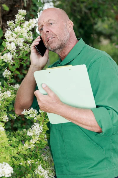 Ώριμος Άντρας Που Χρησιμοποιεί Τηλέφωνο Στον Κήπο — Φωτογραφία Αρχείου