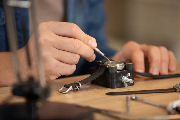 ワークショップのデスクで手首の時計を修理する男のクローズアップ — ストック写真
