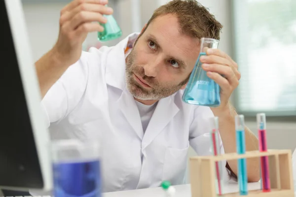 持有瓶蓝色的液体 在实验室中与男性研究员 — 图库照片
