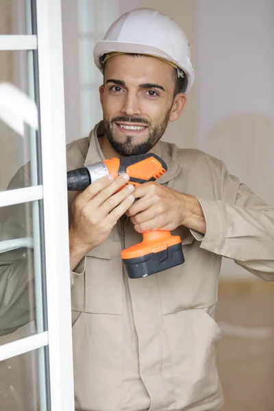smiling man fixing a window handle using cordless screwdriver