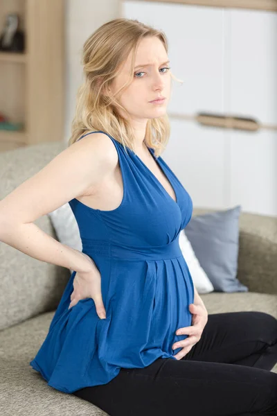 家で腰痛に苦しむ若い妊婦さん — ストック写真