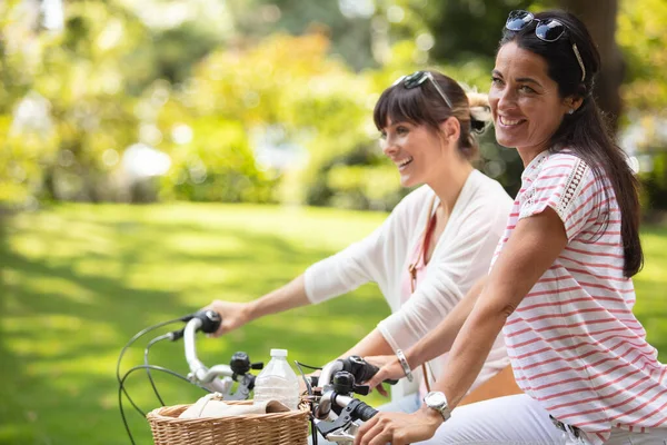 两名骑自行车穿过公园的妇女 — 图库照片