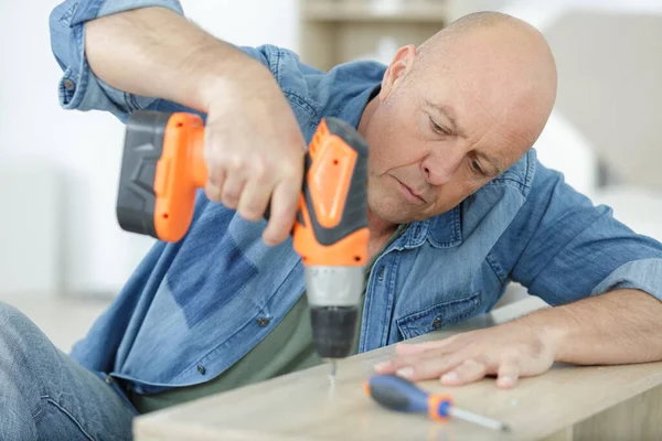Älterer Mann Benutzt Elektrischen Schraubenzieher Bei Der Reparatur Eines Möbels — Stockfoto