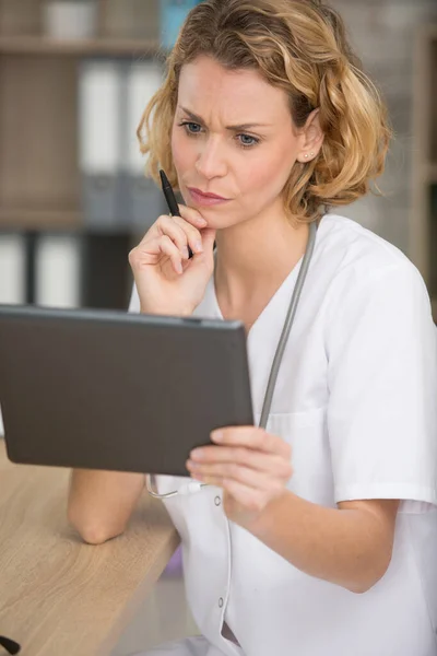 年轻的女医生看着一台平板电脑 — 图库照片