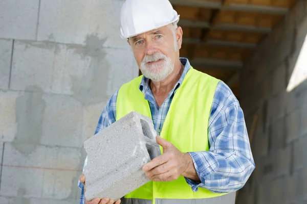 Constructor Senior Está Sosteniendo Ladrillo —  Fotos de Stock
