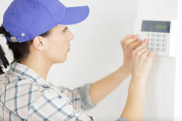 壁に取り付けられたサーモスタット温度を調整する女性 — ストック写真