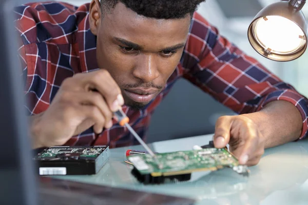 Μαύρος Νεαρός Επισκευάζει Ηλεκτρονικά Τσιπ Κατσαβίδι Στο Τραπέζι — Φωτογραφία Αρχείου