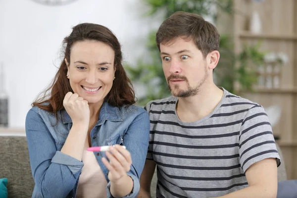 忧心忡忡的男人和他兴奋的妻子一起检查怀孕测试 — 图库照片