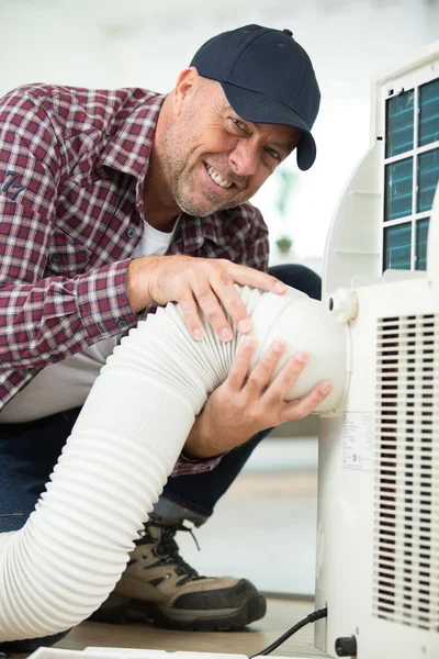man fitting hose to ventilation system