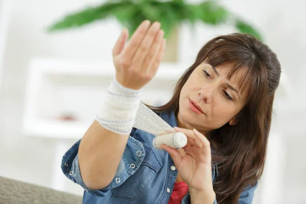 Brunetka Zakładając Bandaż Jej Ranną Rękę Domu — Zdjęcie stockowe