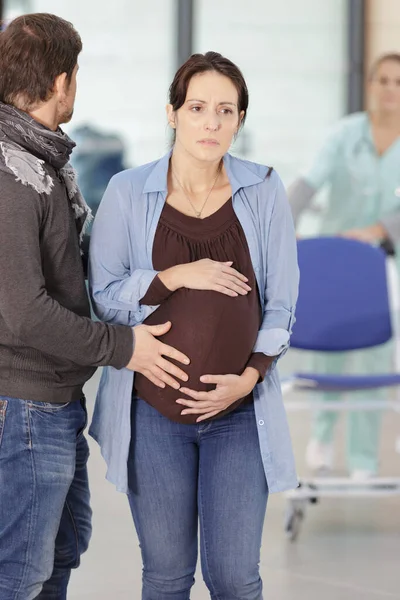 病院の廊下で妊娠中の女性を慰める人 — ストック写真