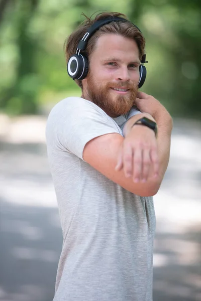 フィットネスセッションの後に腕を伸ばすヘッドフォンを持った男 — ストック写真