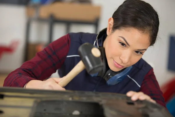young woman working with hammer in industrial building