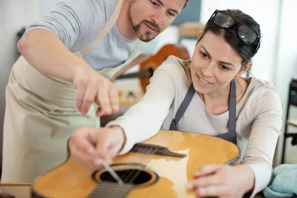 woman learning how to repair a guitar