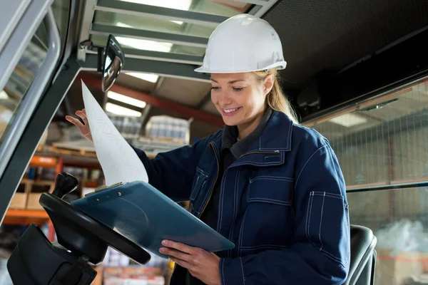 female fork lift truck driver looking at clipboard