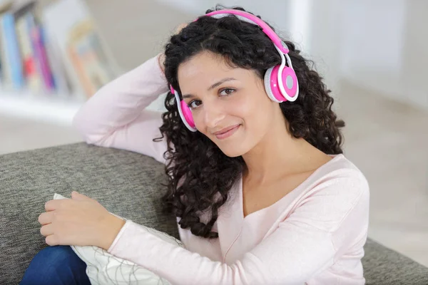幸せな若い女性は家でヘッドフォンで音楽を聴く — ストック写真