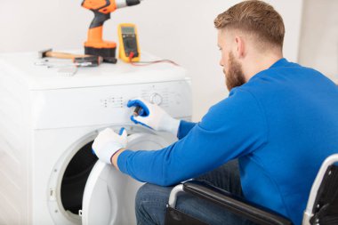 man in wheelchair repairs a tumble dryer clipart