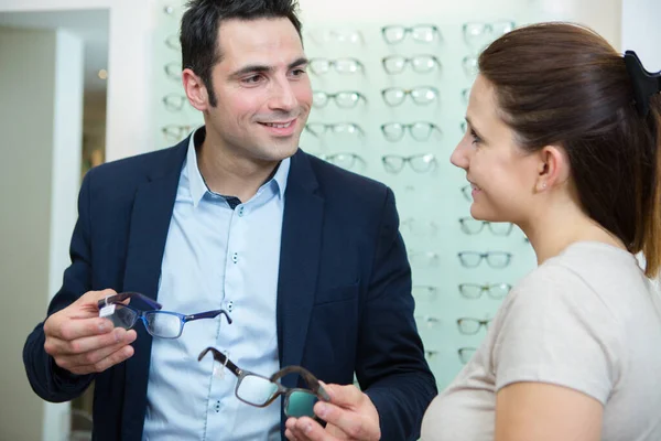 woman and man buying glasses in optician shop