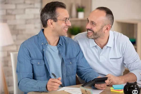 同性伴侣坐在一起 计算家里的家庭预算 — 图库照片