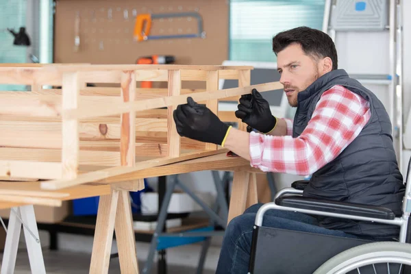 disabled worker in wheelchair working in wood workshop