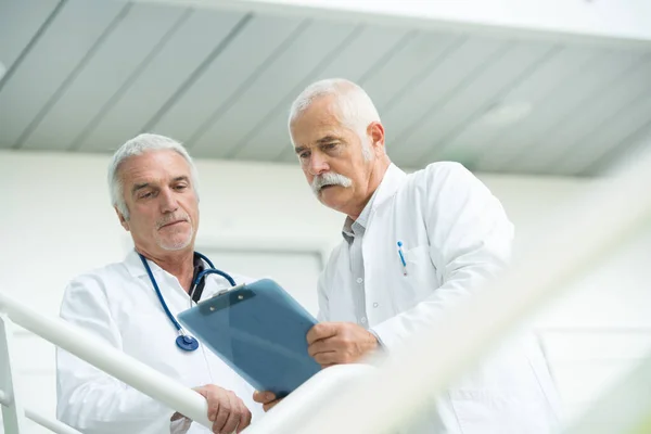 Два Доктора Разговаривают Проходят Через Современную Больницу — стоковое фото