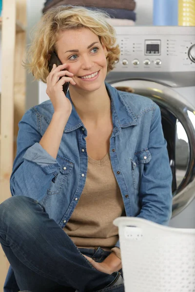happy woman on the phone calling someone near washing machine