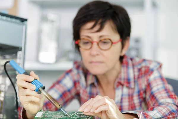 成熟的女性电子工程师焊接计算机 — 图库照片