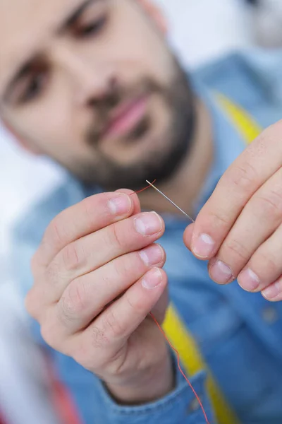 a man trying to thread a needle