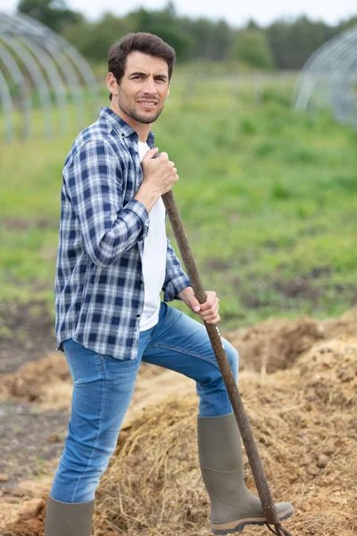 a young man with a shovel in a field
