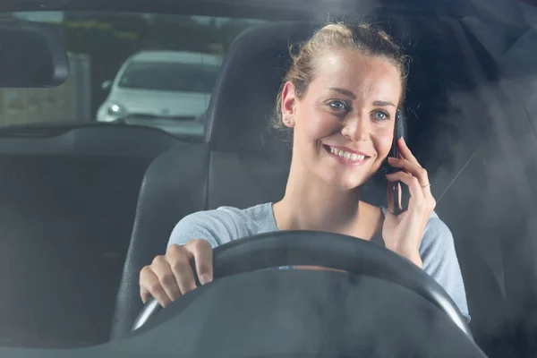 beautiful woman driver on the phone smiling from her car