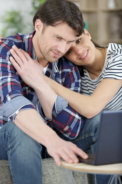 happy man and woman relax on couch hugging watching laptop