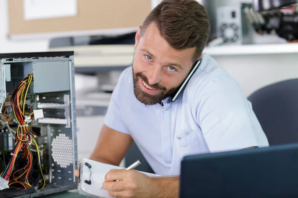 Young Male Contractor Repairing Computer Having Phone Call — Photo