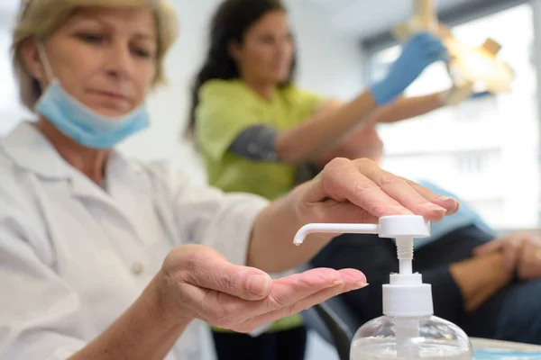 Mature Female Dental Worker Applying Hand Sanitiser — Stock fotografie