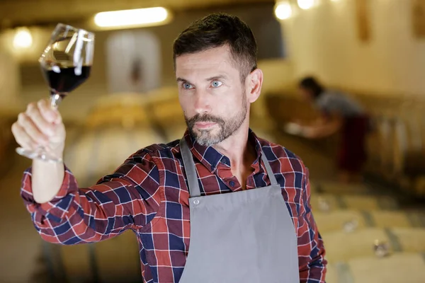 wine producer tilting glass to inspect wine quality