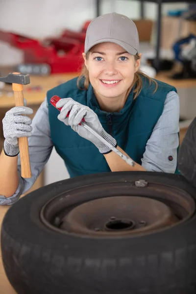 female mechanic using a hammer and chisel on a tyre