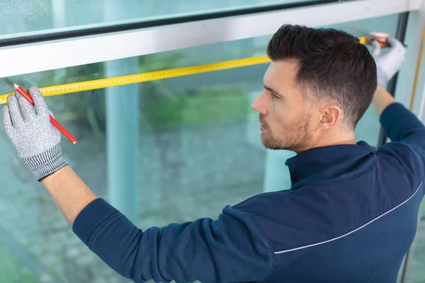 professional male worker measuring window