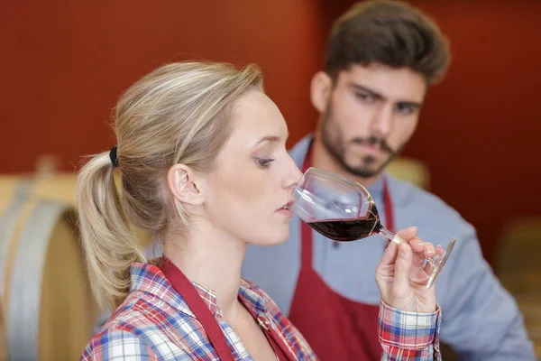 female worker testing red wine in the cellar