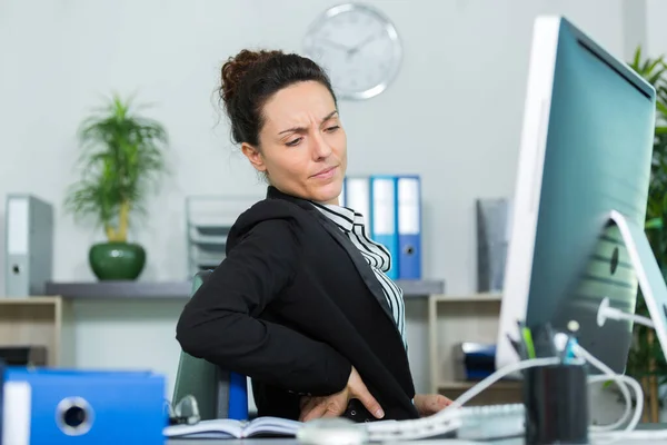 female office worker stretching to ease her painful back