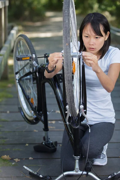 女性は公園内の電動自転車を修理しています — ストック写真