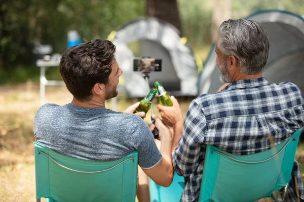 men camping using a moblie phone