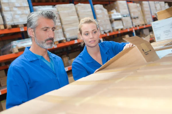 Man and woman in warehouse looking into open cardboard box